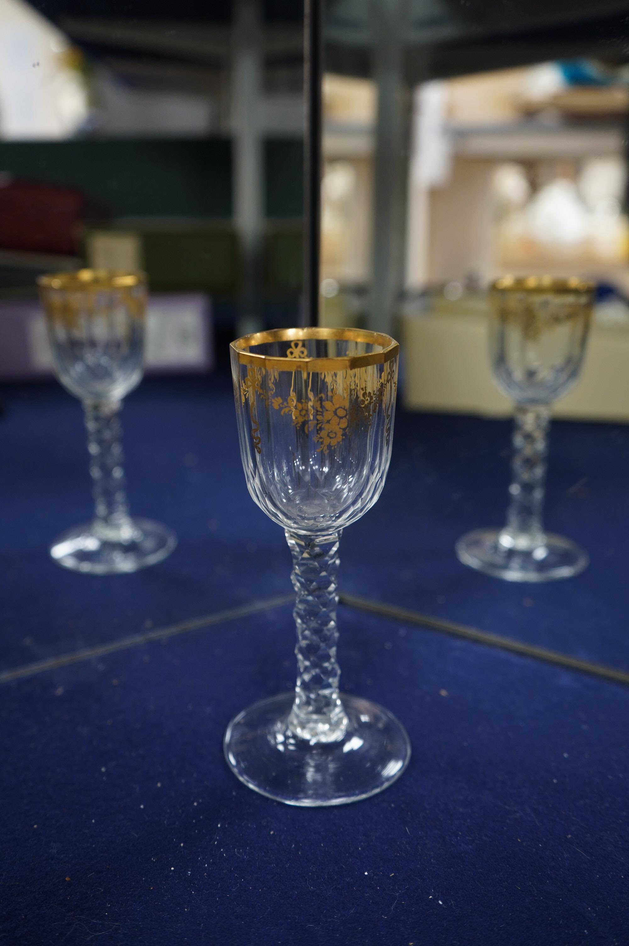 A pair of early 18th century octagonal glasses with gilt floral swagged decoration and facetted stems. Condition - slight wear to gilding otherwise good